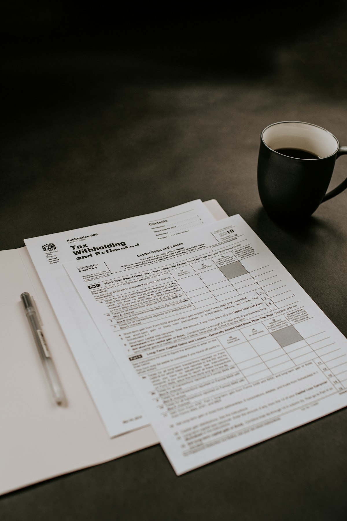 Tax forms and a laptop on a desk